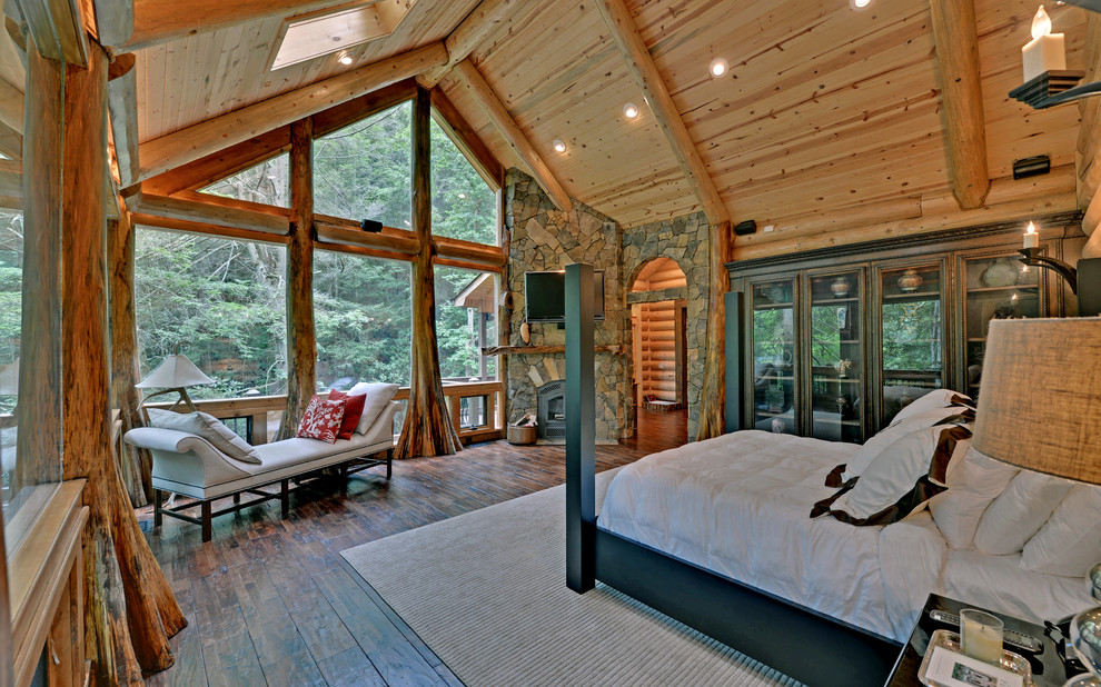 Rustic bedroom in Atlanta with dark hardwood flooring, a stone fireplace surround and a corner fireplace.