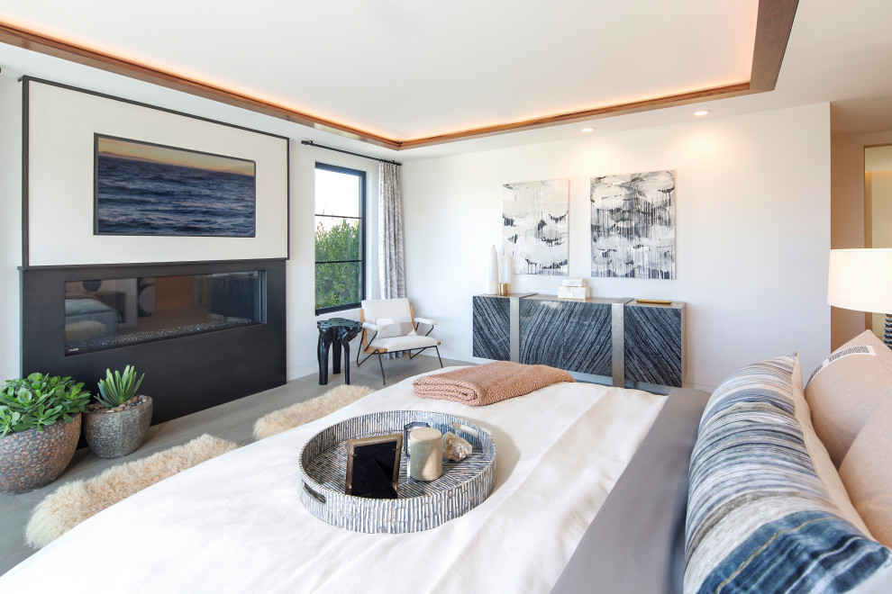 オレンジカウンティにあるコンテンポラリースタイルのおしゃれな寝室 (白い壁、横長型暖炉、グレーの床) のインテリア