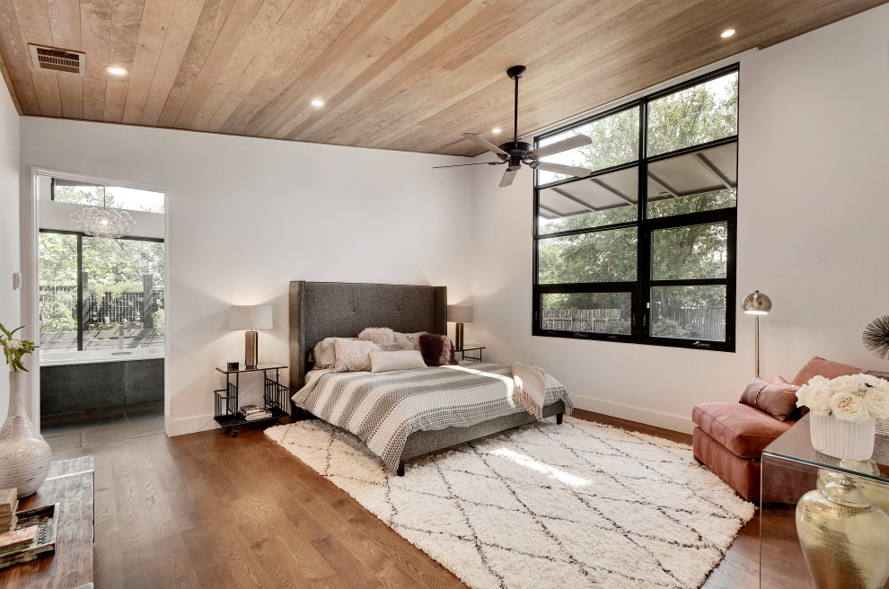 Modernes Hauptschlafzimmer mit weißer Wandfarbe, braunem Holzboden, braunem Boden, gewölbter Decke und Holzdecke in Austin