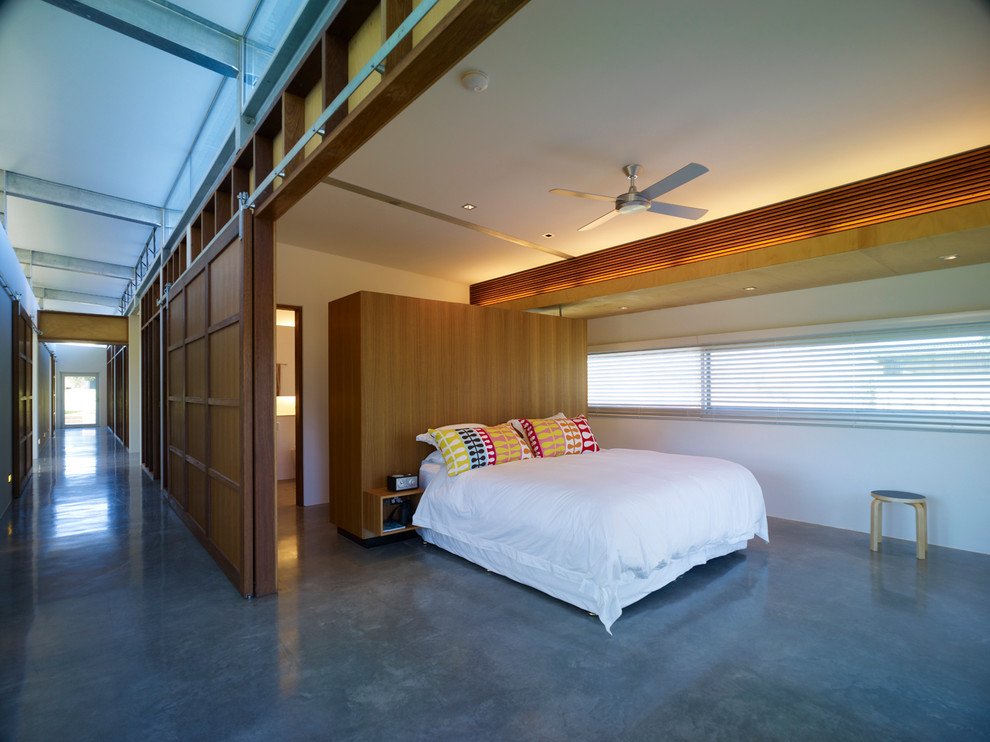 На фото: большая хозяйская спальня в стиле модернизм с белыми стенами и бетонным полом с
