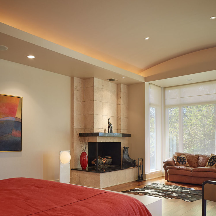 Diseño de dormitorio principal actual grande con paredes multicolor, suelo de madera en tonos medios, chimenea de esquina y marco de chimenea de piedra