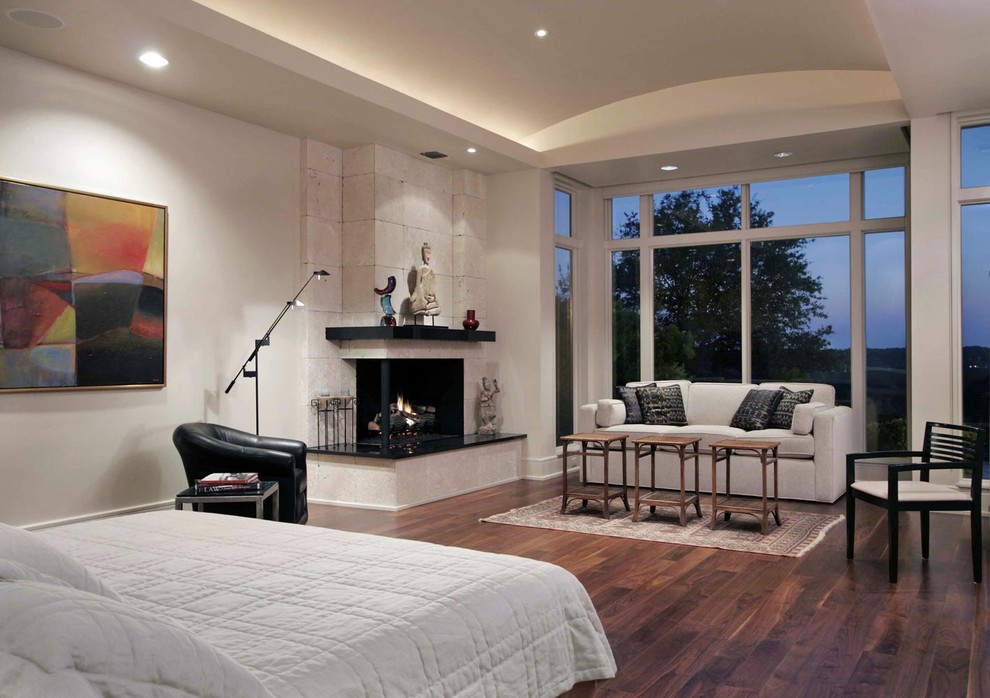 オースティンにある広いコンテンポラリースタイルのおしゃれな主寝室 (白い壁、濃色無垢フローリング、コーナー設置型暖炉、石材の暖炉まわり) のインテリア