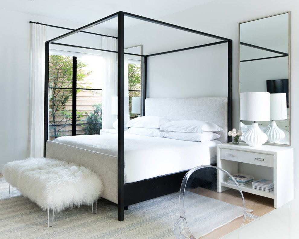 Imagen de dormitorio principal actual de tamaño medio sin chimenea con paredes blancas, suelo de madera clara y suelo beige
