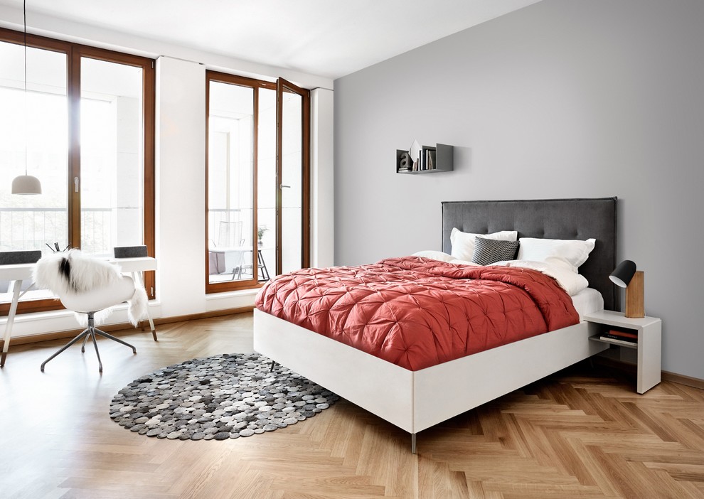 Foto på ett minimalistiskt sovrum, med grå väggar och ljust trägolv