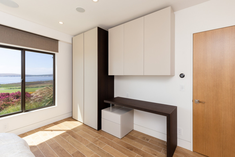 Imagen de habitación de invitados de tamaño medio con paredes blancas y suelo de madera en tonos medios