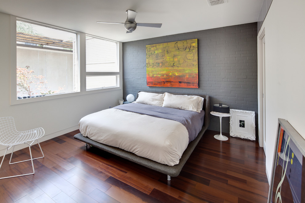 Foto på ett funkis sovrum, med grå väggar och mörkt trägolv