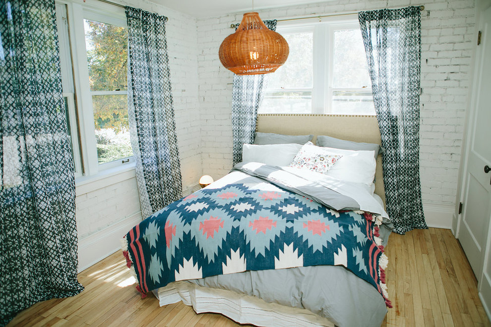 Photo of a small bohemian bedroom in Denver with white walls and light hardwood flooring.