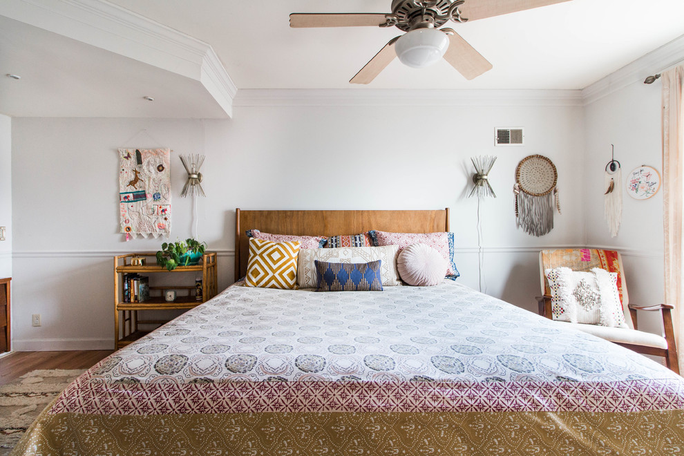 Diseño de dormitorio bohemio con paredes blancas, suelo de madera en tonos medios y suelo marrón