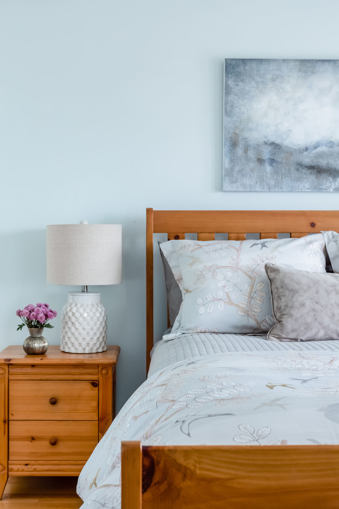 Modelo de dormitorio principal ecléctico de tamaño medio con paredes azules, suelo de madera en tonos medios y suelo marrón