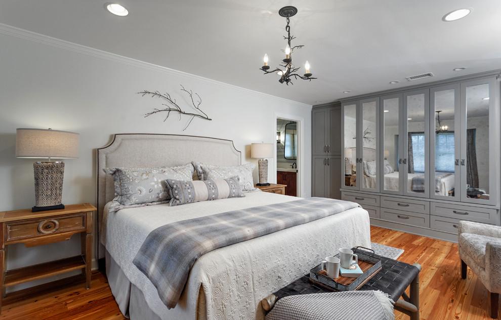 Imagen de dormitorio principal bohemio grande sin chimenea con paredes blancas, suelo de madera en tonos medios y suelo marrón