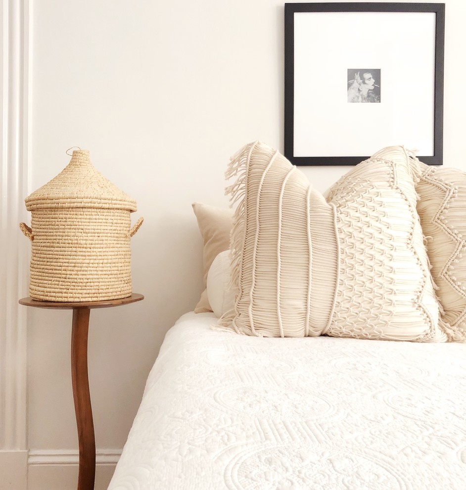 Modelo de habitación de invitados bohemia de tamaño medio con paredes blancas y suelo de madera en tonos medios