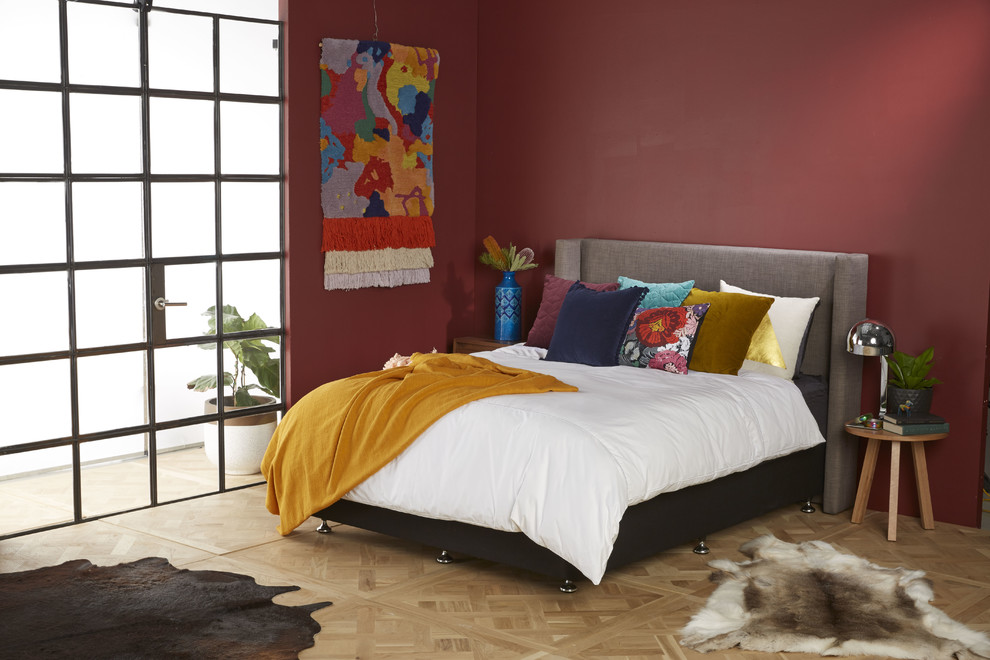 Ejemplo de habitación de invitados moderna de tamaño medio con paredes rojas y suelo de madera clara