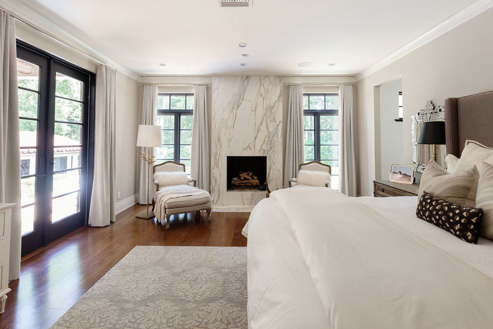 Großes Mediterranes Hauptschlafzimmer mit beiger Wandfarbe, braunem Holzboden, Gaskamin und gefliester Kaminumrandung in Orange County