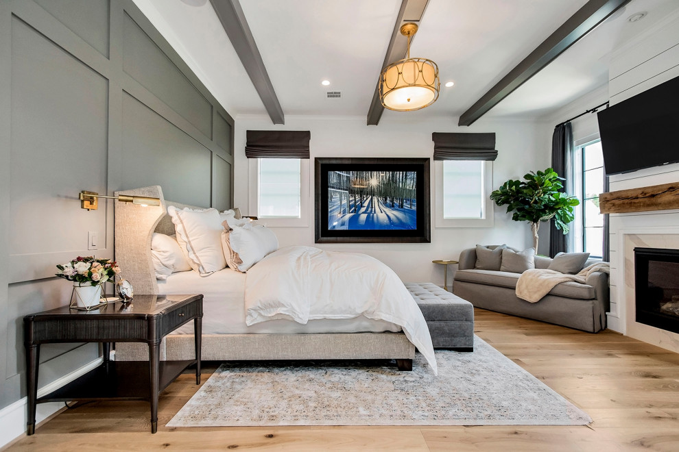 Klassisches Schlafzimmer mit weißer Wandfarbe, braunem Holzboden, Kamin, Kaminumrandung aus Stein und braunem Boden in Houston