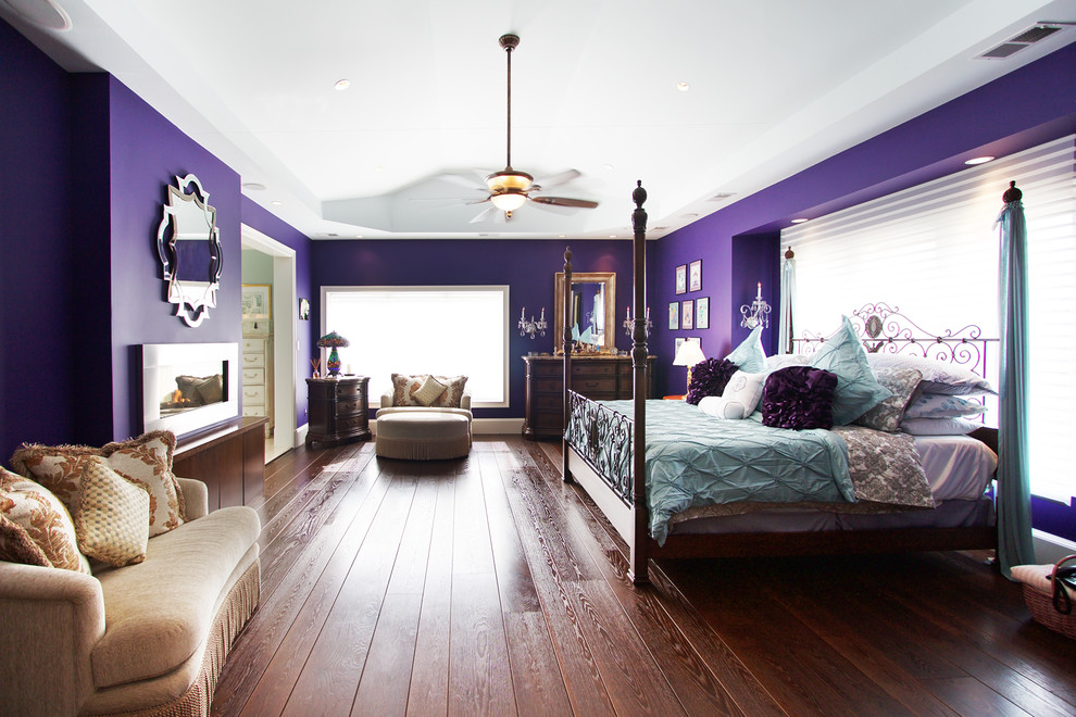 Idées déco pour une chambre parentale contemporaine de taille moyenne avec un mur violet, parquet foncé, une cheminée double-face, un manteau de cheminée en métal et un sol marron.