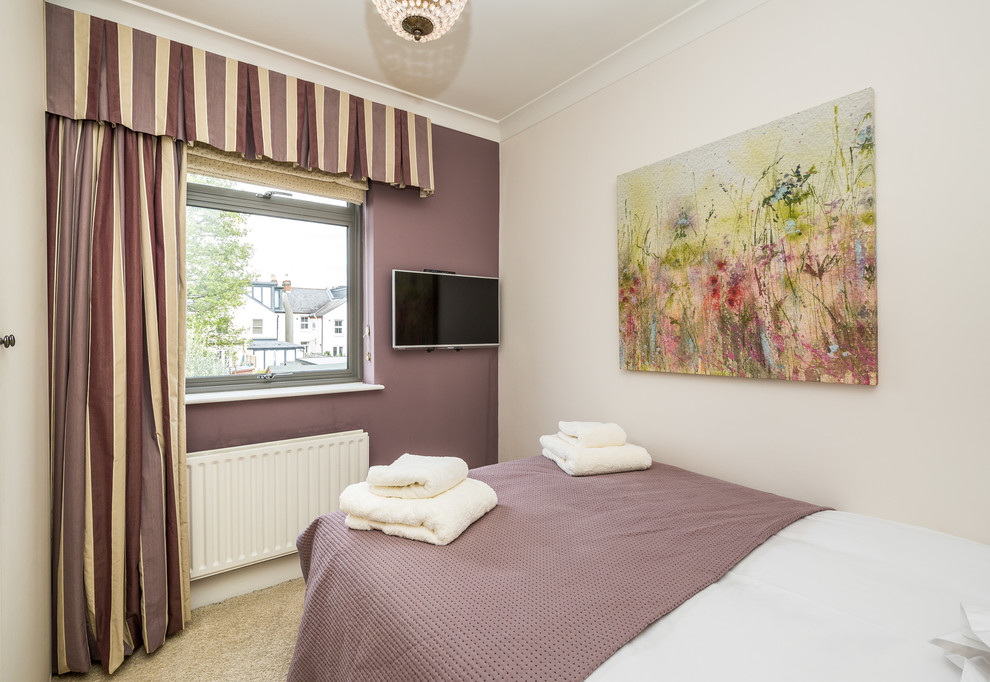Immagine di una piccola camera degli ospiti minimal con pareti viola, moquette, camino classico, cornice del camino piastrellata e pavimento beige
