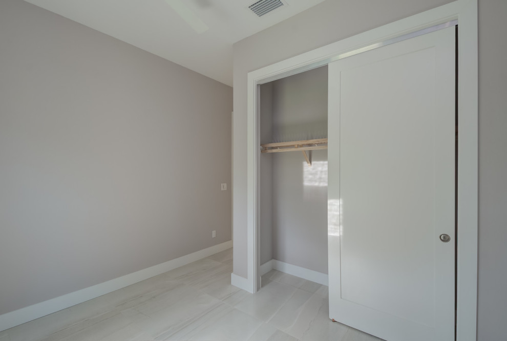 Imagen de habitación de invitados moderna de tamaño medio sin chimenea con paredes grises, suelo de baldosas de porcelana y suelo beige