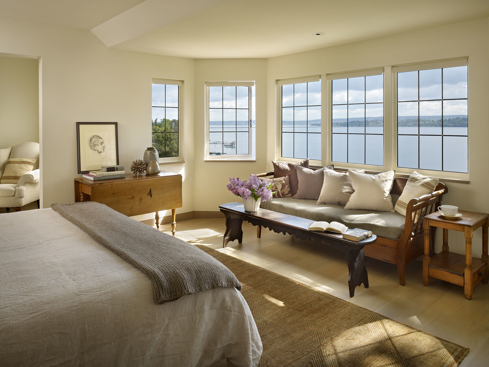 Immagine di una camera da letto design con pareti beige e parquet chiaro