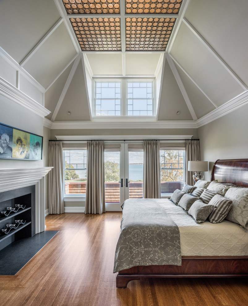 Exempel på ett klassiskt sovrum, med grå väggar, mellanmörkt trägolv, en standard öppen spis och brunt golv