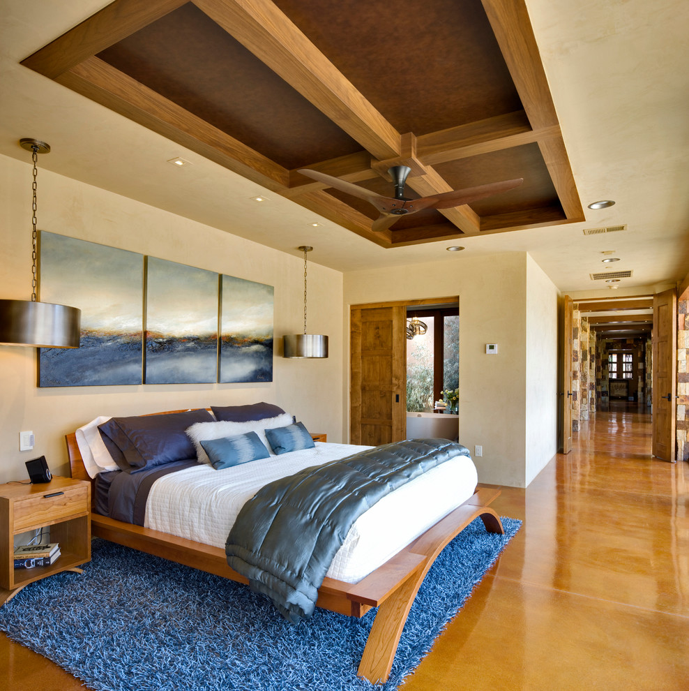 Example of a large trendy master concrete floor and yellow floor bedroom design in Albuquerque with beige walls and no fireplace