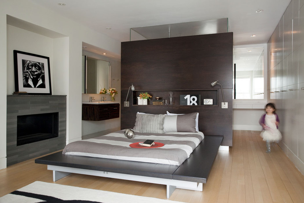 Пример оригинального дизайна: спальня в современном стиле с белыми стенами, светлым паркетным полом и стандартным камином