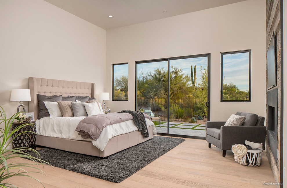 Photo of a medium sized contemporary master bedroom in Phoenix with beige walls, light hardwood flooring, a standard fireplace and a metal fireplace surround.