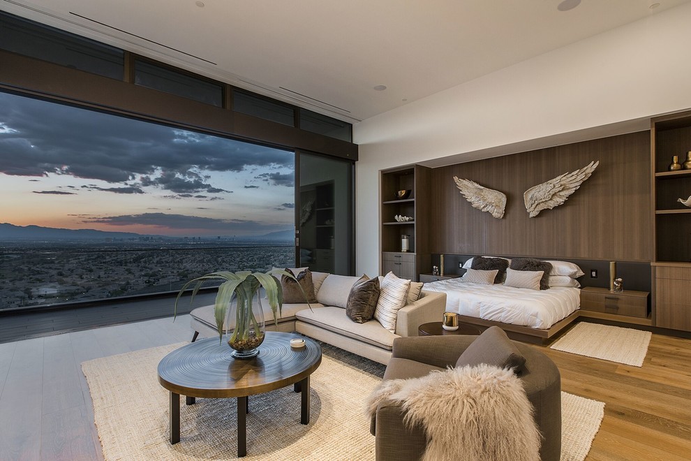 Aménagement d'une très grande chambre parentale contemporaine avec un mur blanc, un sol en bois brun et un sol marron.