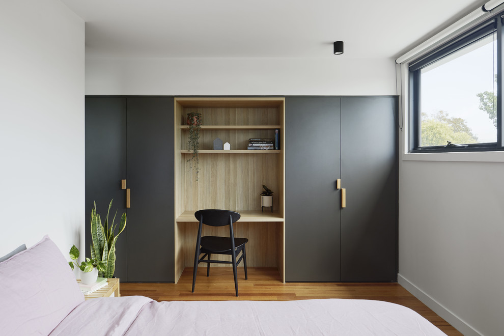 Modernes Schlafzimmer ohne Kamin mit weißer Wandfarbe, braunem Holzboden und braunem Boden in Melbourne