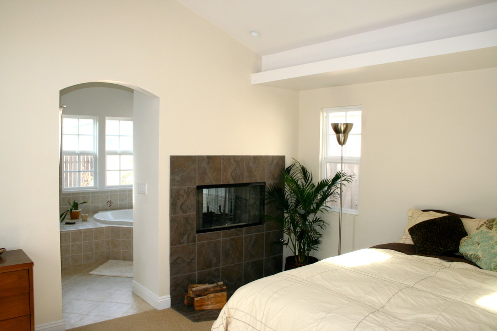 Стильный дизайн: хозяйская спальня среднего размера в современном стиле с полом из керамогранита, двусторонним камином и фасадом камина из плитки - последний тренд