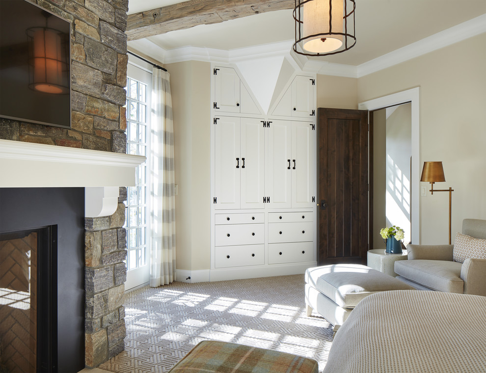Стильный дизайн: большая хозяйская спальня в морском стиле с ковровым покрытием, стандартным камином, фасадом камина из камня, коричневым полом и бежевыми стенами - последний тренд