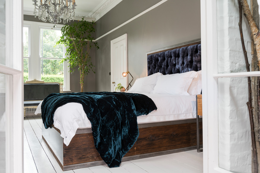 Imagen de dormitorio principal minimalista grande con paredes grises, suelo de madera pintada, estufa de leña, marco de chimenea de madera y suelo blanco