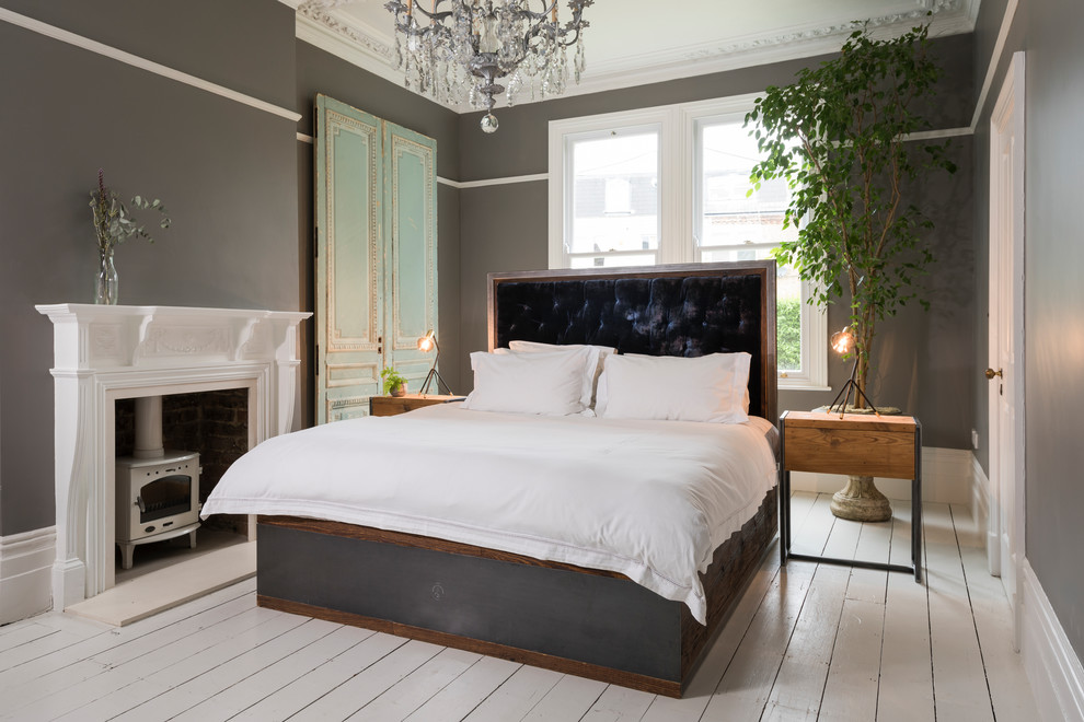 Стильный дизайн: большая хозяйская спальня в стиле модернизм с серыми стенами, деревянным полом, печью-буржуйкой, фасадом камина из дерева и белым полом - последний тренд