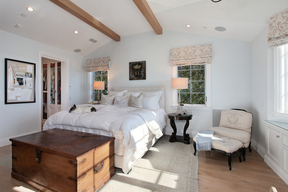 Modelo de dormitorio de estilo de casa de campo sin chimenea con paredes beige y suelo de madera clara