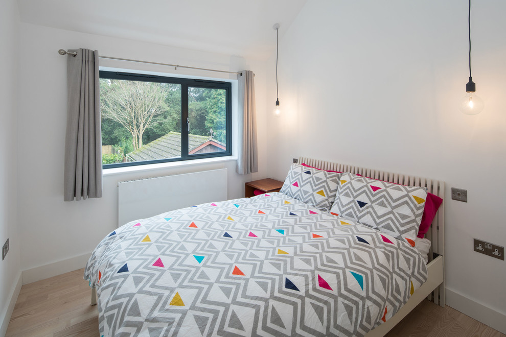 Immagine di una camera degli ospiti nordica di medie dimensioni con pareti bianche, parquet chiaro e pavimento beige