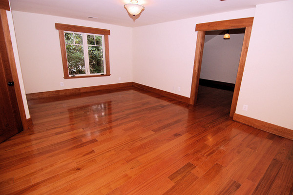 Cette image montre une petite chambre d'amis craftsman avec un mur beige et un sol en bois brun.