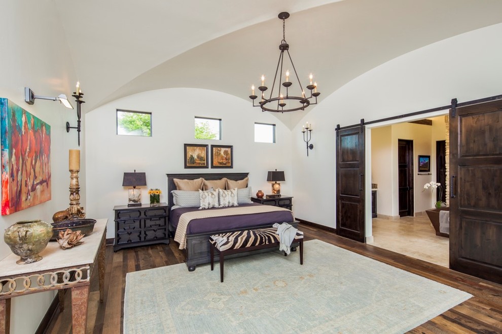 Design ideas for a mediterranean master bedroom in Austin with white walls, medium hardwood flooring and no fireplace.