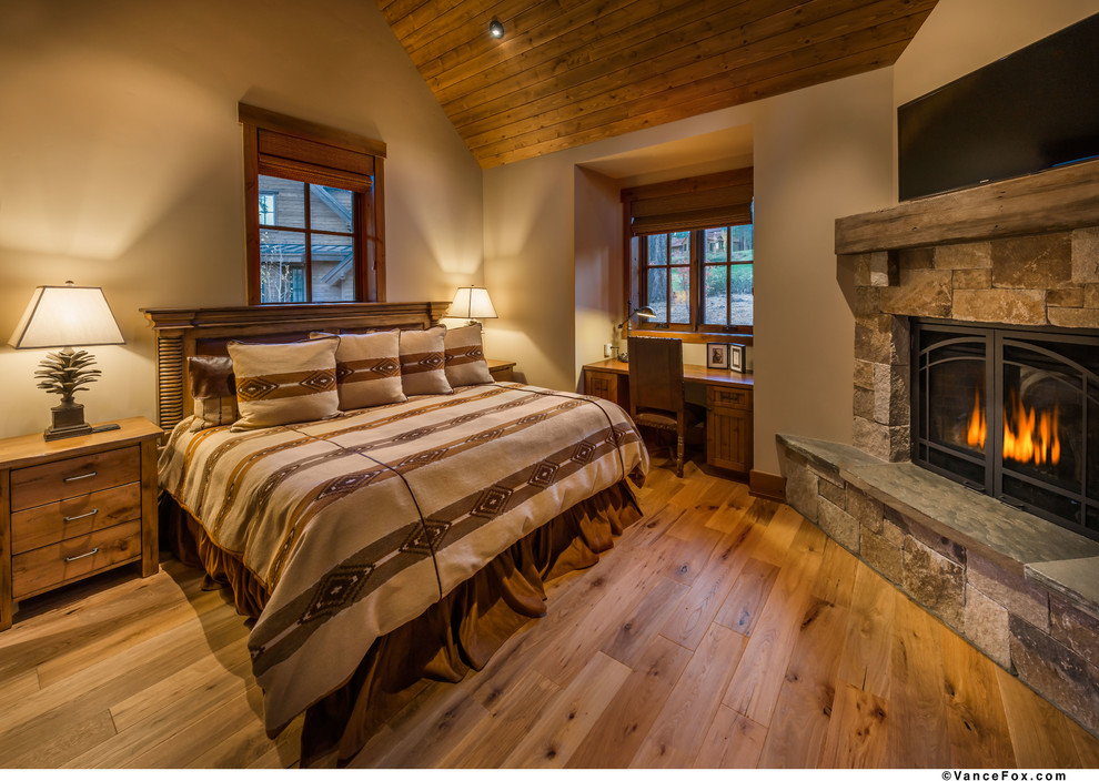 Foto di una camera da letto stile rurale con pareti beige, moquette, camino ad angolo e cornice del camino in pietra