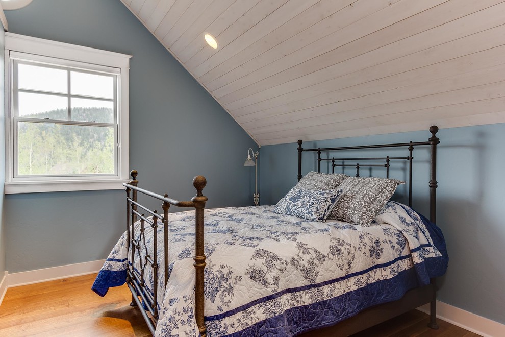 Modelo de habitación de invitados de estilo de casa de campo pequeña con paredes azules y suelo de madera clara