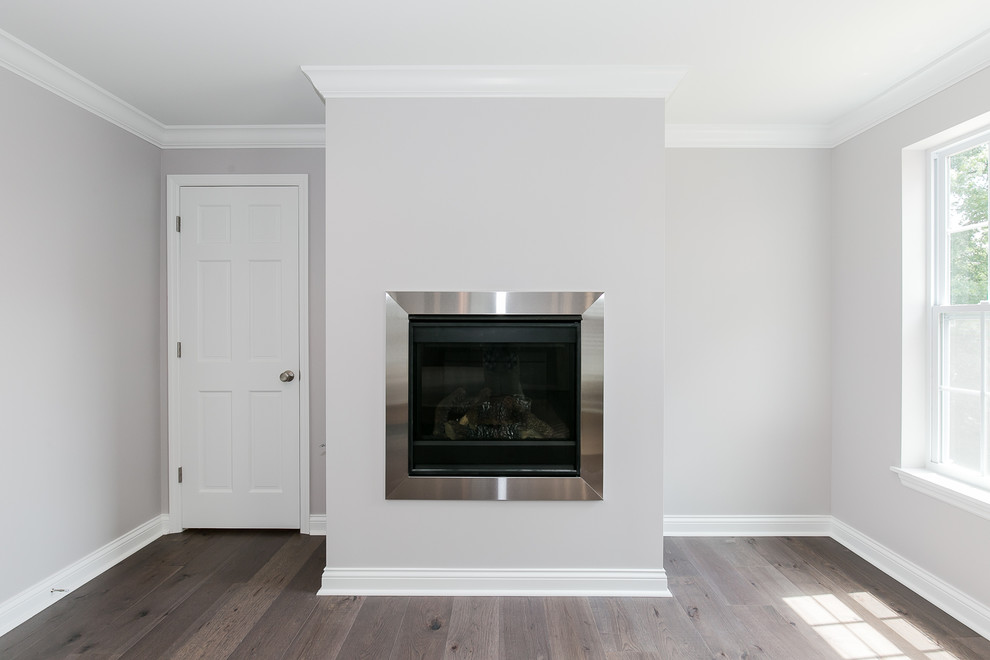 Cette image montre une grande chambre parentale craftsman avec un mur gris, parquet foncé, une cheminée standard, un manteau de cheminée en métal et un sol marron.