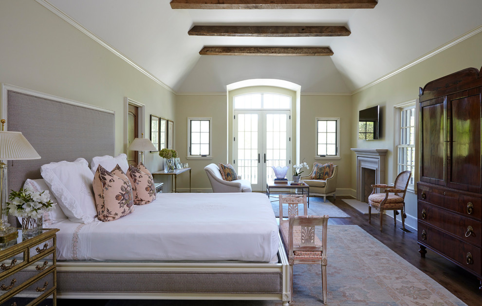 Immagine di una camera matrimoniale chic con pareti beige, parquet scuro e camino classico