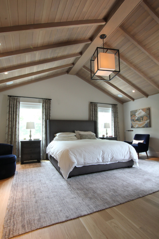 Modelo de dormitorio principal clásico grande sin chimenea con paredes beige y suelo de madera clara