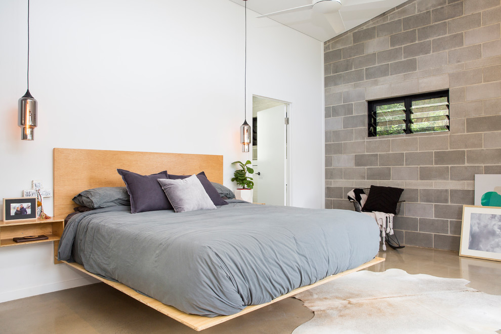 Imagen de dormitorio contemporáneo con paredes blancas y suelo de cemento