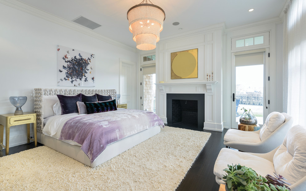 Klassisches Schlafzimmer mit weißer Wandfarbe, dunklem Holzboden, Kamin und braunem Boden in New York