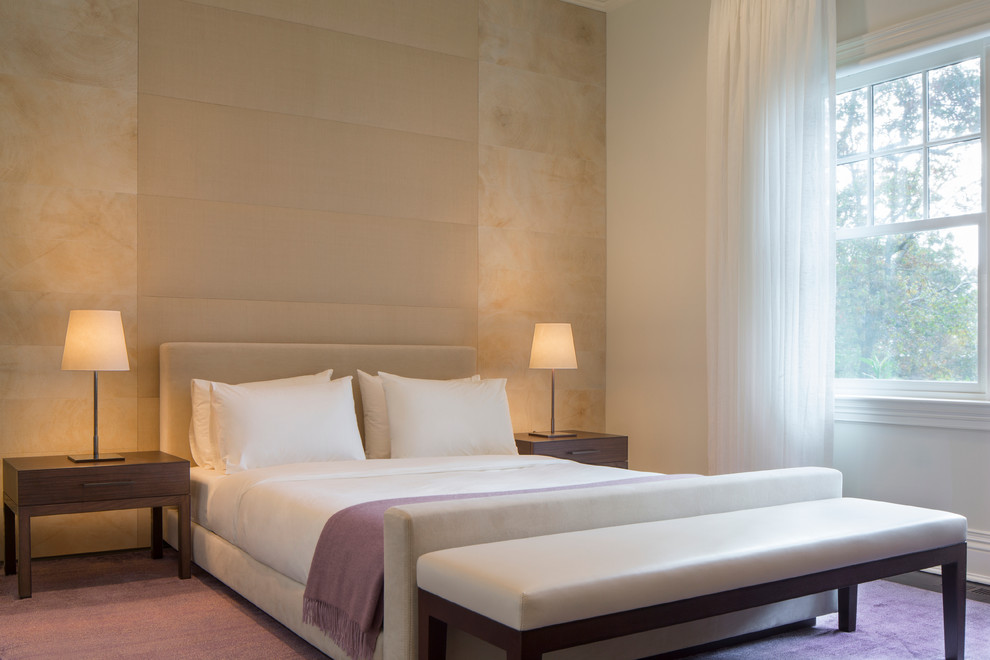 Modelo de dormitorio principal moderno grande sin chimenea con paredes beige y suelo violeta