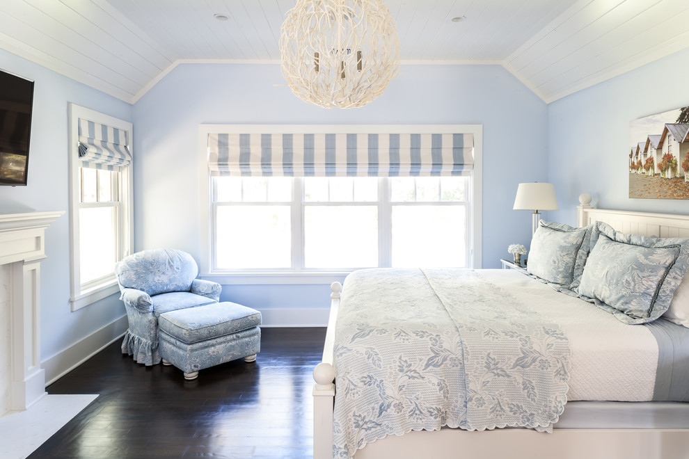 Immagine di una camera matrimoniale costiera di medie dimensioni con pareti blu, parquet scuro e camino classico