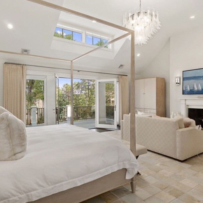 Imagen de dormitorio principal costero grande con paredes blancas, suelo de travertino y suelo beige