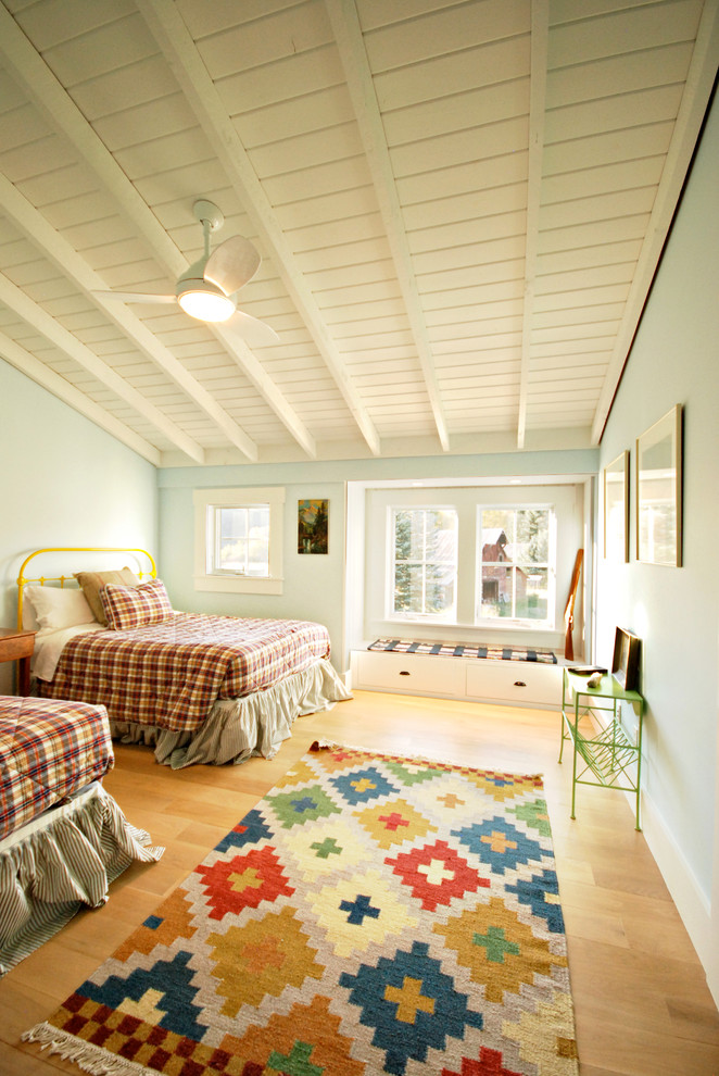 Large farmhouse guest bedroom in Other with blue walls, light hardwood flooring, no fireplace and brown floors.