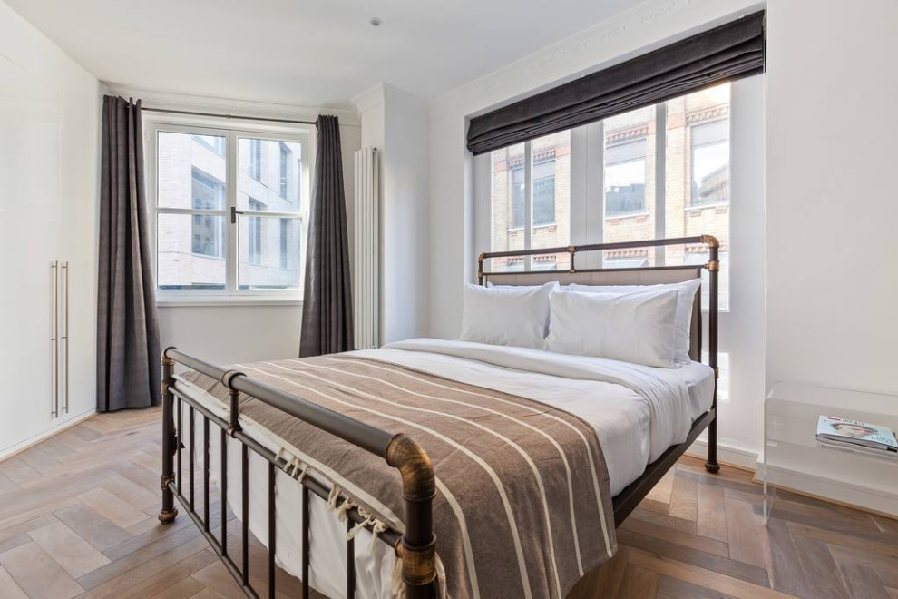 Foto de dormitorio principal urbano de tamaño medio con paredes blancas, suelo de madera en tonos medios y suelo gris