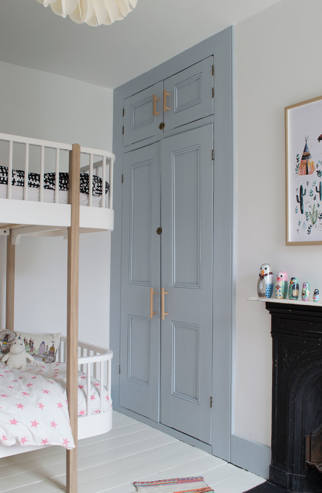 Example of a mid-sized danish painted wood floor bedroom design in Kent with white walls, a standard fireplace and a metal fireplace