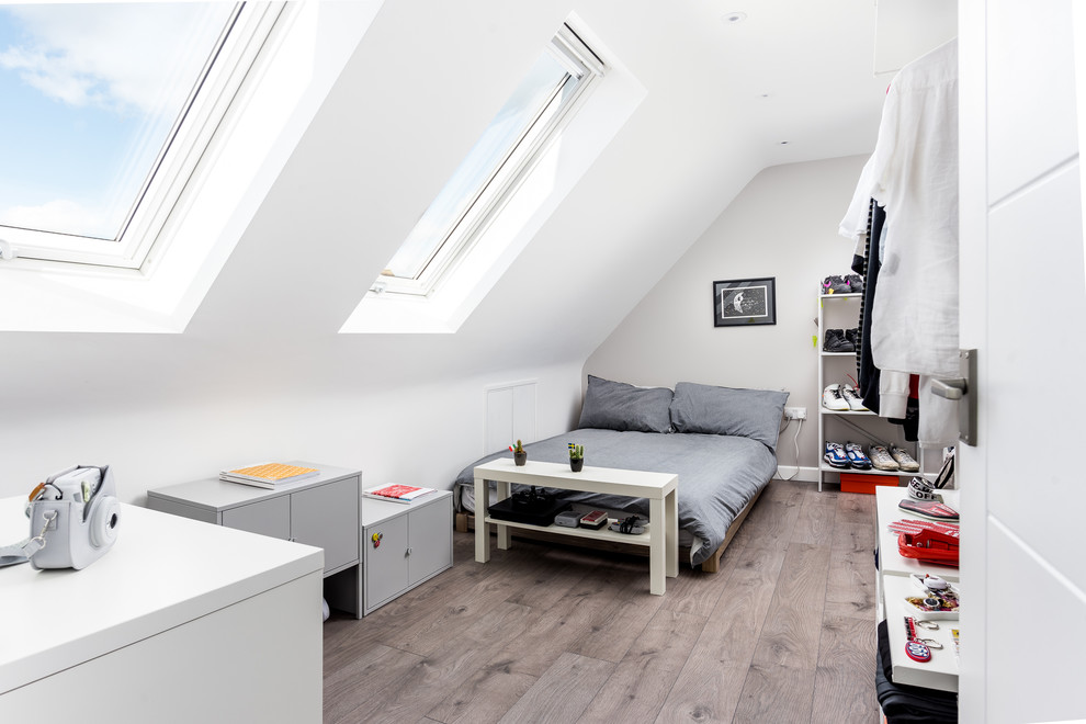 Design ideas for a medium sized modern grey and brown loft bedroom in Sussex with beige walls, laminate floors, no fireplace and brown floors.
